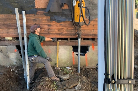 Engineer standing next to post hole digger for new helical piers in Worcester, Massachusetts